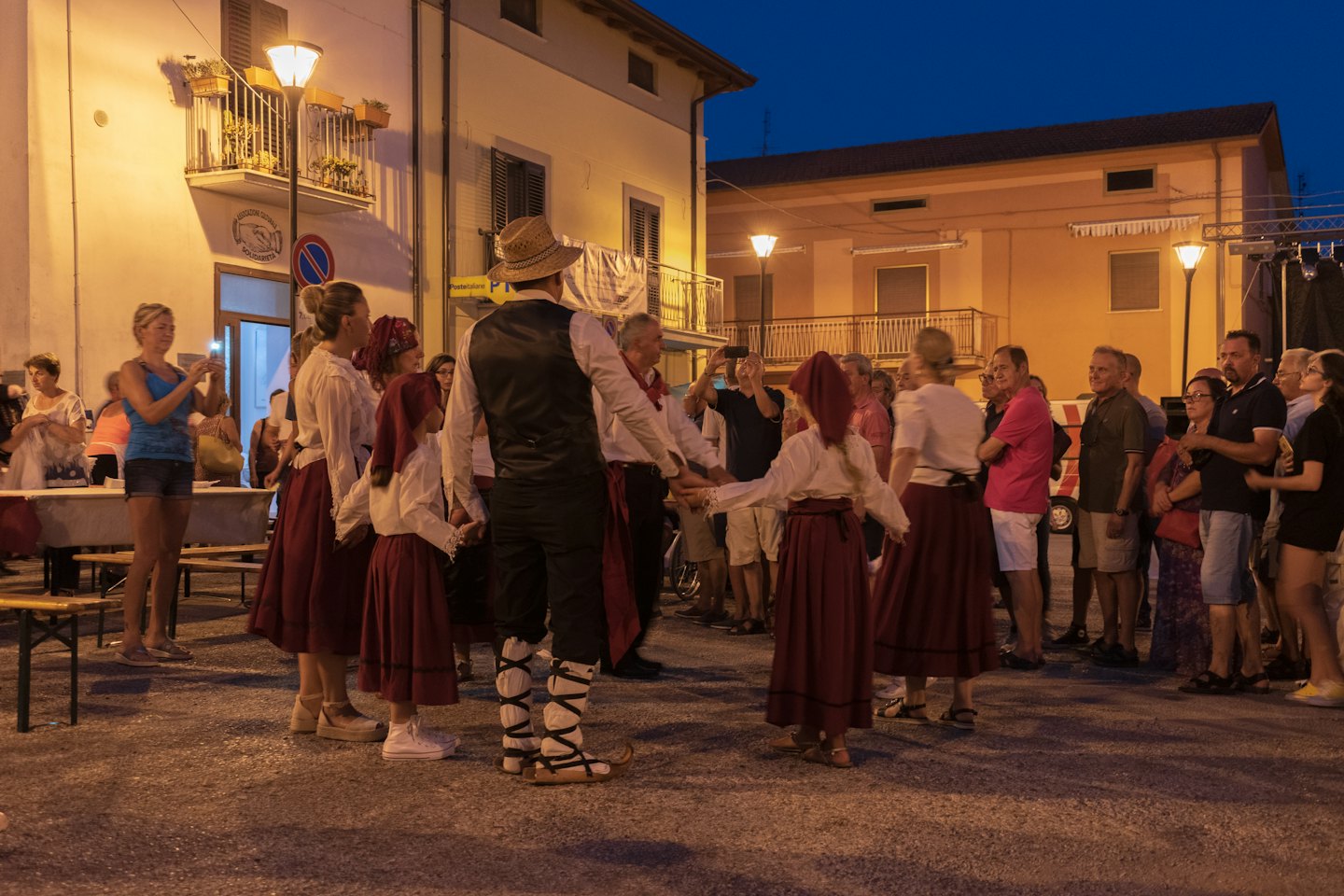 Menschen in traditionellen Kostümen tanzen im Kreis im Dorf.