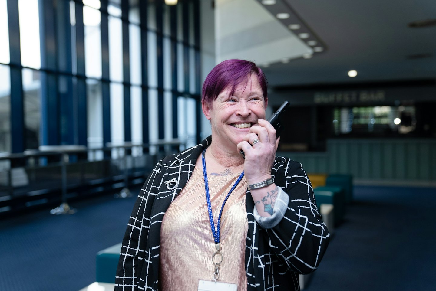 Frau mit lila Haaren spricht auf einer Konferenz in ein Funkgerät.